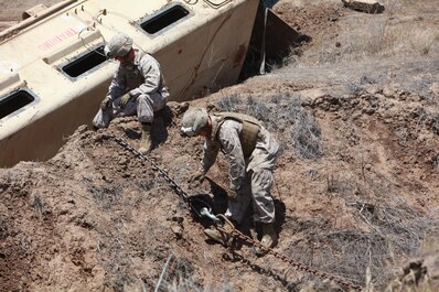 Wrecker operators with Maintenance Company, 1st Maintenance Battalion, Combat Logistics Regiment 15, 1st Marine Logistics Group, attach a tow chain to a simulated disabled Mine Resistant Ambush Protected vehicle during a vehicle-recovery exercise aboard Camp Pendleton, Calif., May 20, 2013. (U. S. Marine Corps photo by Lance Cpl. Cody Haas/Released)