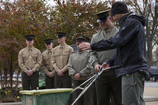 Graham Davis, Smithsonian Gardens horticulturist, shows Sgt. James Hamby, a Marine with Guard Company, Marine Barracks Washington, D.C., how to use a seed spreader in front of the National Museum of American History in Washington, Nov. 12. After the lesson, the Marines participated in the Flanders Field Project, where they spread seeds over the front lawn of the museum to recreate the poppy fields that blossomed on the war-stricken land of Europe in the aftermath of WWI.