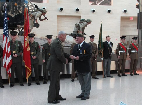 Gen. John M. Paxton Jr., assistant commandant of the Marine Corps, presents Barry Fletcher with a gold badge in recognition of his 50 years of service in the Green Howards Association. Fletcher was a member of the Yorkshire Regiment of the British Army in 1963, and was present in Tripoli when the units exchanged plaques for the second time. The first plaque exchange took place in Shangai, China in 1927. 