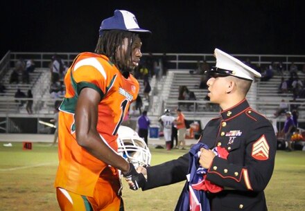 Marine Corps recruiter Sgt. Mario Sanchez with Recruiting Substation Fort Myers, Recruiting Statin Fort Lauderdale, Fla., presents a jersey to Ryeshene Bronson from Dunbar High School Oct. 11, 2013, for being selected to play in the Semper Fidelis All American Bowl. Bronson, a senior wide receiver at Dunbar, excels in the class room and is a prominent mentor in his community. Selected to play for his character as a whole, Bronson said he is excited about the opportunity and that he is "ready to go."   