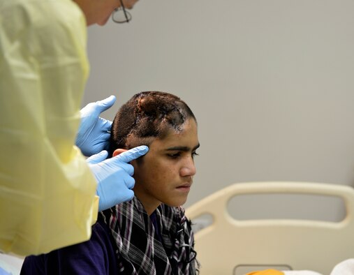 Lt. Col. David Jones, 455th Expeditionary Medical Group pediatrician, prepares to examine a 12-year-old boy’s head in the Craig Joint Theater Hospital on Bagram Airfield, Afghanistan, Oct. 20. The boy recently had a surgery to help release pressure on his brain and is being treated for an infection. Jones is a native of San Antonio. (U.S. Air Force photo/ Staff Sgt. Stephenie Wade) 
