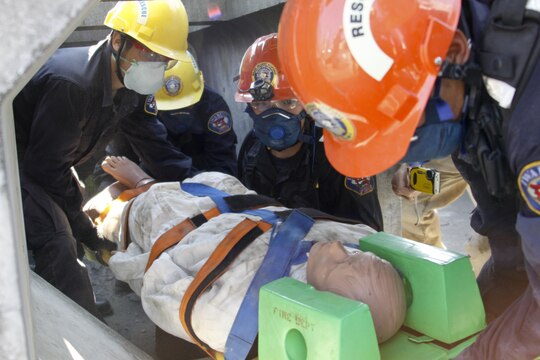 Firefighters from Marine Corps Air Station Iwakuni, Japan, extract a training dummy from a simulated collapse for their practical application exam during the Urban Search and Rescue Technical Search Training course Aug. 28, 2013.