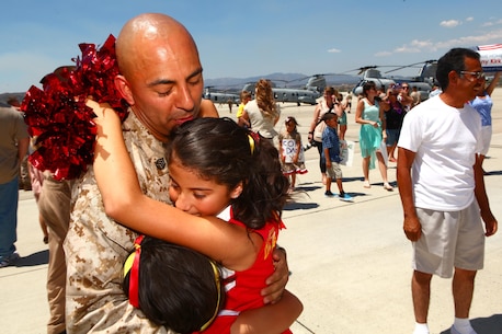 Staff Sgt. Natividad Herrera, a helicopter mechanic with Marine Medium Helicopter Squadron 364 "Purple Foxes," holds his daughters for the first time in eight months during a homecoming ceremony aboard Marine Corps Air Station Camp Pendleton, Calif., May 13. While deployed with the 15th Marine Expeditionary Unit, his squadron provided round-the-clock aerial support to multiple missions all over the world.