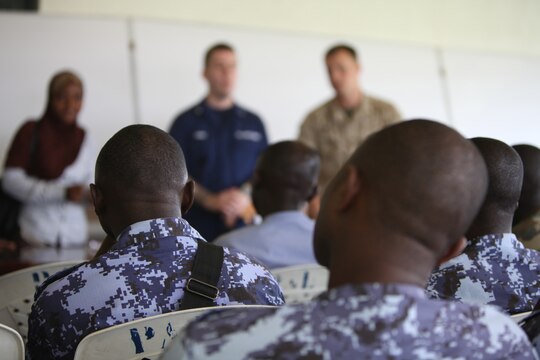 A group of sailors with the Togolese Navy listen to Lance Cpl. Tyler Jackson, a Marine with Special-Purpose Marine Air-Ground Task Force Africa 14.1, and Petty Officer 3rd Class Brian Spence, a Coastguardsman with U.S. Coast Guard Station Seattle, discuss small-boat engine mechanics through an interpreter in Lomé, Togo, March 25. After the classroom period, the U.S. service members and Togolese sailors went outside to fix an ailing small-boat engine together.