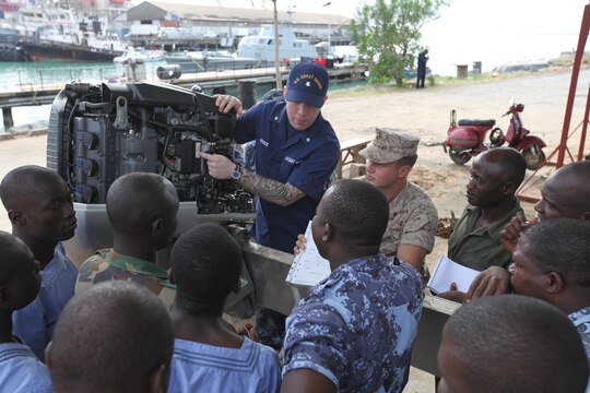 Petty Officer 3rd Class Brian Spence, a Coastguardsman with U.S. Coastguard Station Seattle, explains the electronic control module of a small-boat engine a group of sailors from the Togolese Navy in Lomé, Togo, March 25. Spence flew from Seattle to attend a week-long training program designed to demonstrate proper small-boat engine mechanics to a group of sailors from the Togolese Navy.