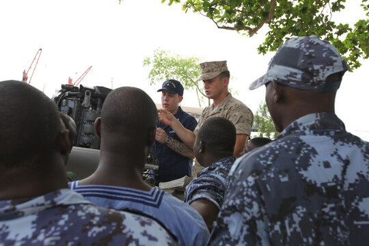 A group of sailors with the Togolese Navy watch as Lance Cpl. Tyler Jackson, a Marine with Special-Purpose Marine Air-Ground Task Force Africa 14.1, and Petty Officer 3rd Class Brian Spence, a Coastguardsman with U.S. Coast Guard Station Seattle, discuss small-boat engine mechanics in Lomé, Togo, March 25. Jackson and Spence put together a week-long training program of classroom instruction and practical application so the two groups of service members could partner together to fix engines. Established in 2011, Special-Purpose Marine Air-Ground Task Force Africa 14.1 is charged with supporting U.S. Africa Command and Marine Corps Forces Europe and Africa’s theater security cooperation requirements.