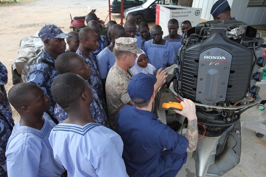 A group of sailors with the Togolese Navy watch as Lance Cpl. Tyler Jackson, a Marine with Special-Purpose Marine Air-Ground Task Force Africa 14.1, and Petty Officer 3rd Class Brian Spence, a Coastguardsman with U.S. Coast Guard Station Seattle, discuss small-boat engine mechanics in Lomé, Togo, March 25. Jackson and Spence put together a week-long training program of classroom instruction and practical application so the two groups of service members could partner together to fix engines. Established in 2011, Special-Purpose Marine Air-Ground Task Force Africa 14.1 is charged with supporting U.S. Africa Command and Marine Corps Forces Europe and Africa’s theater security cooperation requirements.