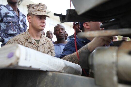 Lance Cpl. Tyler Jackson, a Marine with Special-Purpose Marine Air-Ground Task Force Africa 14.1, looks on as Petty Officer 3rd Class Brian Spence, a Coastguardsman with U.S. Coast Guard Station Seattle, explains the electronic control module on a small-boat engine to a group of sailors from the Togolese Navy in Lomé, Togo, March 25. Jackson and Spence put together a week-long training program of classroom instruction and practical application so the two groups of service members could partner together to fix engines. Established in 2011, Special-Purpose Marine Air-Ground Task Force Africa 14.1 is charged with supporting U.S. Africa Command and Marine Corps Forces Europe and Africa’s theater security cooperation requirements.
