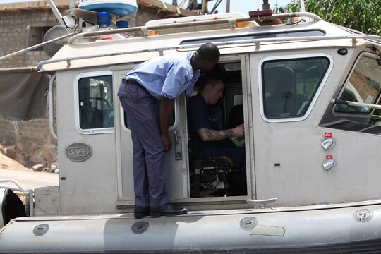 A sailor with the Togolese Navy watches as Petty Officer 3rd Class Brian Spence, a Coastguardsman with U.S. Coast Guard Station Seattle, demonstrates how to properly diagnose engine problems from within the cockpit of a small boat in Lomé, Togo, March 25. Spence put together a week-long training program of classroom instruction and practical application so the two groups of service members could partner together to fix engines. Established in 2011, Special-Purpose Marine Air-Ground Task Force Africa 14.1 is charged with supporting U.S. Africa Command and Marine Corps Forces Europe and Africa’s theater security cooperation requirements.
