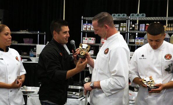 Aaron Williams presents Gunnery Sgt. Matthew Jacobs with the 1st place trophy during the Boiling Points competition held at the Del Mar Fairgrounds April 16. Boiling Points is a competition hosted by Aaron Williams, the corporate division chef for Food Fanatics, Los Angeles. The competition challenged the Marine Corps, Army, Navy and Coast Guard to go head-to-head in a 45-minute cooking competition. The Marine team took 1st place with their dish of an appetizer of fried eggplant and seared scallop caprese, and an entrée of seared duck, sweet potatoes and a fruit medley with a star fruit and horn melon sauce. Jacobs is the enlisted aid for the I Marine Expeditionary Force’s commanding general.