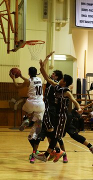Jon Cadavos, a senior with the Matthew C. Perry Samurai basketball team, goes around three defenders to score during the first of two home games against the Zama American High School Trojans, Dec. 12, 2014, at the high school gymnasium aboard Marine Corps Air Station Iwakuni, Japan. The Samurai defeated the Trojans 45-28 in the first game and 59-54 in the second. 