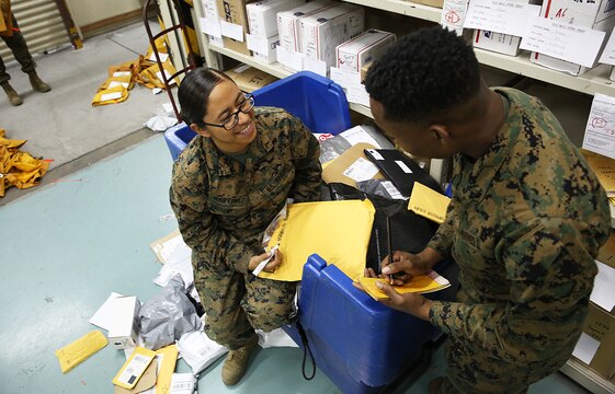 Pfc. Maria Martinez, directorary clerk at the Mainside Postal Office aboard Marine Corps Air Station Iwakuni, Japan, goes through mail on Dec. 11, 2014. More than 700 pounds of mail are sent per day and 3,500 pounds of mail are received per day during the busy holiday season months of late November to mid-January.