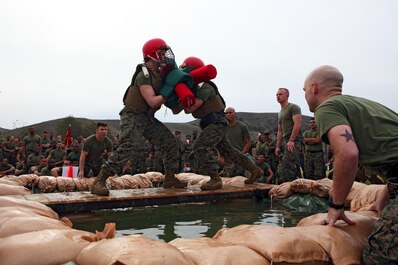 Marines with Combat Logistics Regiment 15, 1st Marine Logistics Group, face off in a pugil-stick match over three feet of water during the regiment’s physical training competition aboard Camp Pendleton, Calif., Jan. 24, 2014. In addition to sparring with pugil sticks, the Marines participated in a boots and utilities formation run and competed in body jousting, an event in which Marines raced across a wet and soapy tarp with unit-decorated refrigerator boxes over their heads. The winner of the overall physical fitness competition was Maintenance Battalion.