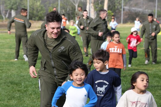 A Marine volunteer with Marine Aviation Logistics Squadron (MALS) 16, 3rd Marine Aircraft Wing, encourages children of Morning Creek Elementary School, San Diego, during the school’s annual Jog-a-Thon Feb. 6. MALS-16 has been involved with the “Partnerships in Education” program with the school for the past eight years.