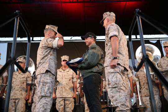 MARINE CORPS AIR STATION MIRAMAR, Calif. – Maj. Gen. Michael Rocco, left, 3rd Marine Aircraft Wing commanding general, presents an American flag to Gary Sinise, actor and musician with the Lt. Dan Band, after a colors ceremony aboard Marine Corps Air Station Miramar, Calif., July 7. Sinise performed for service members and their families with his band. 