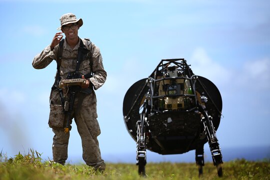 Lance Cpl. Brandon Dieckmann, infantryman with India Company, 3rd Battalion, 3rd Marine Regiment, and native of Las Vegas, leads the Legged Squad Support System through a grassy area at Kahuku Training Area, July 12, 2014, during the Rim of the Pacific 2014 exercise. The LS3 is experimental technology being tested by the Marine Corps Warfighting Lab during the Advanced Warfighting Experiment. It is programmed to follow an operator through terrain, carrying heavy loads like water and food to Marines training. There are multiple technologies being tested during RIMPAC, the largest maritime exercise in the Pacific region. This year's RIMPAC features 22 countries and around 25,000 people. (U.S. Marine Corps photo by Cpl. Matthew Callahan/RELEASED)