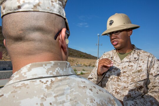 Lance Cpl. Thomas Flanigan, a marksmanship instructor at the Carlos Hathcock Range Complex aboard Marine Corps Air Station Miramar, Calif., offers guidance to a shooter after a course of fire, July 29. The Corps’ newest pistol marksmanship qualification, the Combat Pistol Program, implemented October 2013, allows marksmanship coaches Corpswide to make training more realistic for the thousands of Marines and Sailors who qualify annually.