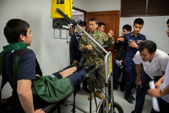 Petty Officer 1st Class Amaflor Pinera demonstrates the procedure of a portable x-ray at the Flight-line Aid Station with personnel from Wing One Hospital, Royal Thai Air Force, aboard Wing One Royal Thai Air Force Base, Nakhon Ratchasima, Kingdom of Thailand, Feb. 10 as part of Exercise Cobra Gold 2014. CG 14 is an annual multinational exercise conducted in the Kingdom of Thailand designed to exercise multinational joint interoperability. Pinera is an x-ray technician with Marine Wing Support Squadron 171, Marine Aircraft Group 12, 1st Marine Air Wing, III Marine Expeditionary Force.