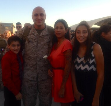 Bianca Frost, center right, stands with her husband and children during a homecoming event. Frost, a Committed and Engaged Spouse, volunteers regularly to help others and overcome daily stressors. 