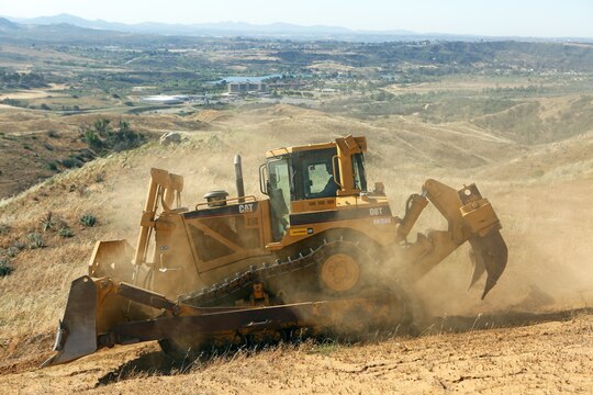 Lance Cpl. Brady Calvin, engineer equipment operator, Support Company, 7th Engineer Support Battalion, 1st Marine Logistics Group, plows brush along a firebreak path using a V8T Dozer aboard Camp Pendleton, Calif., May 13, 2014. Facilities Maintenance Division and seven Marines with 7th ESB, 1st MLG, began creating firebreaks May 6, 2014 in an effort to contain wildfires that may start on base and will continue to create them through Aug. 10, 2014. The FMD employees and 7th ESB Marines are still slated to meet this completion date even with the fire that destroyed 6,000 acres and caused hundreds of service members and their families to evacuate their on-base homes, May 14, 2014.