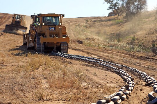 A V8T Dozer drags a chain across a firebreak to flatten its surface as another dozer clears brush from the path, aboard Camp Pendleton, Calif., May 13, 2014. Facilities Maintenance Division and seven Marines with 7th Engineer Support Battalion, 1st Marine Logistics Group, began creating firebreaks May 6, 2014 in an effort to contain wildfires that may start on base and will continue to create them through Aug. 10, 2014. The FMD employees and 7th ESB Marines are still slated to meet this completion date even with the fire that destroyed 6,000 acres and caused hundreds of service members 
and their families to evacuate their on-base homes, May 14, 2014.

