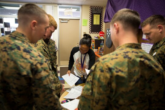 Mrs. Amy P. Budde, 2nd grade teacher with Morning Creek Elementary School, hands out an assignment to Marine volunteers for the students in the class, Nov. 5. The volunteers would help with classwork and physical activities, such as team sports.