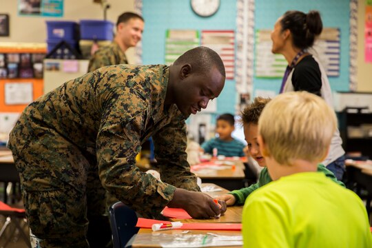 Cpl. Paa Kwesi “P.K.” Coleman, an aviation supply and accounting specialist with Marine Aviation Logistics Squadron (MALS) 16 helps some students with an assignment at Morning Creek Elementary School, Nov. 5. Marines visit the school to help mentor students in Mrs. Amy P. Budde’s 2nd grade class every Wednesday.