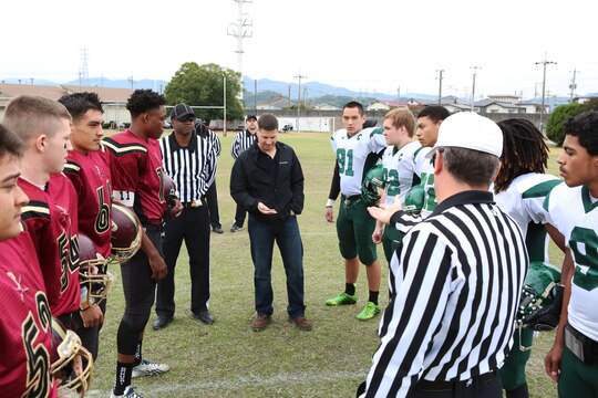 Col. Robert Boucher, commanding officer of Marine Corps Air Station Iwakuni, Japan, flips the coin to begin the 2014 Department of Defense Dependents Schools Far East Division II Football Championship Game at the Matthew C. Perry High School football field aboard MCAS Iwakuni Nov. 8, 2014. The Daegu Warriors won the toss and went on to defeat the M. C. Perry Samurai 60-50.