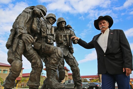 John Phelps, designer for the monument, poses with his creation after an unveiling ceremony Nov. 12 at the Wounded Warrior Battalion, Camp Pendleton. The sculpture is based on the Operation Phantom Fury photograph 'Hell House' of then 1st Sgt. Bradley Kasal being carried out of a house by two lance corporals after a firefight where Kasal sustained injuries. "The monument is a symbol of camaraderie that's important to Marines, not only in combat but in the healing process as well, " said Robin Kelleher, president of Hope for the Warriors, which  contributed to constructing the monument.