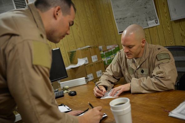 (Right) U.S. Air Force Maj. Vincent Sherer, 455th Ai r Expeditionary Wing, A-10 Thunderbolt II pilot, reviews checklists before a sortie at Bagram Airfield, Afghanistan Aug. 5, 2014.  Sherer has been flying for 12 years and has deployed to Bagram four times.  He is deployed from Davis-Monthan Air Force Base, Ariz. and a native of Portland, Ore. (U.S. Air Force photo by Staff Sgt. Evelyn Chavez/Released)