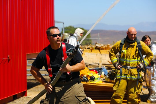 Rich Clarke, a train-the-trainer instructor for Fire Training Structures, tests water hoses at a training facility during an exercise conducted by the Camp Pendleton Fire Department and the Marine Corps Air Station Camp Pendleton’s Aircraft Rescue Fire Fighting unit on a controlled burn training facility at the 25 Area here.
“This is a Flashover simulator,” said Clarke. “This teaches firefighters how to prevent the rapid combustion of off-gas created by burned materials.”
