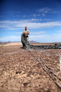 1st Lt. Stephen Shepard, Landing Support Company, Air Delivery platoon commander, folds a Joint Precision Airdrop System parachute during testing of the system Aug. 26, 2014, at Yuma Proving Ground, Ariz. The JPADS systems use GPS, a modular autonomous guidance unit, or MAGU, a parachute and electric motors to guide cargo within 150 meters of their target points. To test its precision, the Marines used a series of palletized loads attached to parachutes with the GPS integrated system and dropped them from various heights. (U.S. Marine Corps photo by Sgt. Laura Gauna/ released)