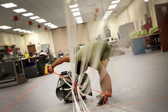 Lance Cpl. Chiem T. Saeteurn of Seattle strings together a Joint Precision Airdrop System parachute during testing of the system Aug. 26, 2014, at Yuma Proving Ground, Ariz. The JPADS systems use GPS, a modular autonomous guidance unit, or MAGU, a parachute and electric motors to guide cargo within 150 meters of their target points. To test its precision, the Marines used a series of palletized loads attached to parachutes with the GPS integrated system and dropped them from various heights. (U.S. Marine Corps photo by Sgt. Laura Gauna/ released)