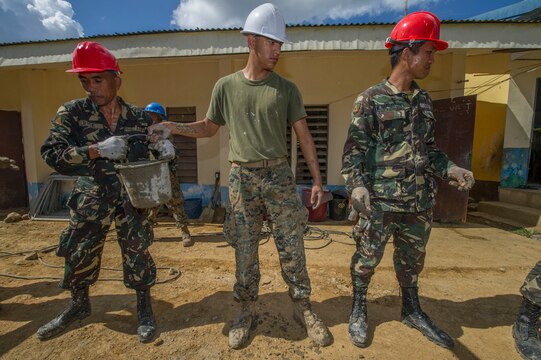 U.S. Marine Lance Cpl. Ramon Perez, center, a civil affairs Marine assigned to III Marine Expeditionary Force, is ‘shoulder-to-shoulder’ with Armed Forces of the Philippines engineers from the 522nd Engineering Construction Battalion passing a bucket filled with cement for placement at Don Joaquin Elementary School in Tapaz, Philippines, during Balikatan 2015, April 9. The engineers, along with U.S. Navy Seabees from Naval Mobile Construction Battalion 5, are part of the Combined-Joint Civil-Military Operations Task Force located on the island of Panay constructing two classrooms at the school. Balikatan, which means “shoulder to shoulder” in Filipino, is an annual bilateral training exercise aimed at improving the ability of Philippine and U.S. military forces to work together during planning, contingency, humanitarian assistance and disaster relief operations. 