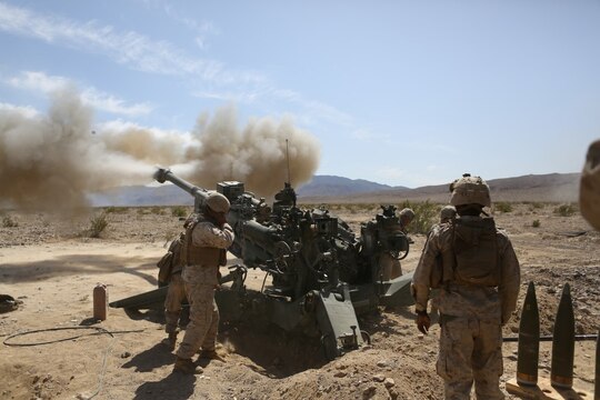 Corporal Osmar S. Gorish, a section chief for Battery A, 1st Battalion, 11th Marine Regiment, 1st Marine Division, observes a round being shot down range during Exercise Desert Scimitar 2015 aboard Marine Corps Air Ground Combat Center Twentynine Palms, Calif., April 20, 2015. The tough, realistic live-fire training central to Desert Scimitar allows Division units to train in order to maintain readiness and meet current and real-world operational demands.
