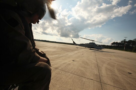 Sgt. Corey Burgess awaits take off across from an AH-1W Super Cobra during a training exercise testing a digital interoperability system at Marine Corps Air Station Cherry Point, North Carolina, July 24, 2015 Digital interoperability is the technology capable of increasing prowess on the battlefield.  The exercise included Marine Light Attack Helicopter Squadron 467, Marine Unmanned Aerial Vehicle Squadron 2, and U.S. Marine Corps Forces, Special Operations Command, testing a LINK 16 conversion system for one of the first times within an explicitly rotary-wing exercise.  Burgess is a Bell UH-1 crew chief with HMLA-467.