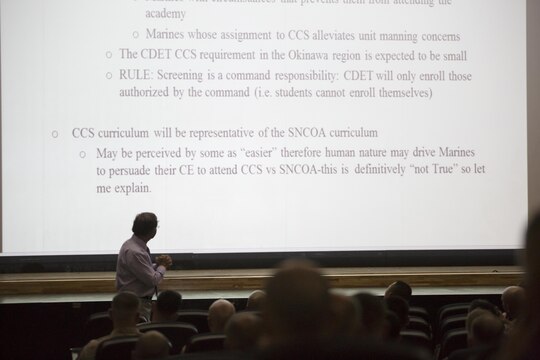 Dr. James P. Hopkins, College of Distance Education and Training Okinawa regional director, briefs staff noncommissioned officers (SNCO) of Marine Corps Air Station Iwakuni, Japan, and Marine Aircraft Group 12 on the Career Course Seminar (CCS) Distance Education Program (DEP), and officers on the Blended Seminar Program at the Sakura Theater aboard station, Aug. 5, 2015. CCS offers staff sergeants the opportunity to attend either the resident career course at one of the four SNCO academies or in the CCS DEP where they will interact with a professional instructor and a collection of their peers in an academic environment.