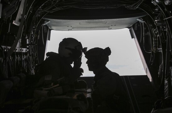 Sgt. Nicholas G. Tissandier, left, a crew chief with Marine Medium Tiltrotor Squadron 263, relays information to Sgt. Kurt Kusterbeck, right, a jump master with 2nd Radio Battalion, on board an MV-22 Osprey during para-operations above Marine Corps Base Camp Lejeune, N.C., Aug. 18, 2015. Tissandier was one of two crew chiefs assisting in the para-jump operations, relaying information to the jump master or preparing cargo for drop. (U.S. Marine Corps photo by Cpl. Paul S. Martinez/Released)