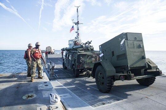 A Marine with Combat Logistics Regiment 25 drives a High Mobility Multipurpose Wheeled Vehicle (HMMWV) and trailer off of a Roll-on/Roll-off Discharge Facility and onto an Improved Navy Lighterage System during an in-stream Marine Prepositioning Force Exercise, Aug. 19, 2015. Marines with CLR-25 and sailors with Naval Beach Group 2 joined forces for the latest iteration of MPFEX, which saw service members offloading the USNS 1st Lt. Jack Lummus using Lift-on/Lift-Off and Roll-on/Roll-off procedures off the coast of Marine Corps Support Facility Blount Island, Fla. (U.S. Marine Corps photo by Sgt. Shawn Valosin/Released)