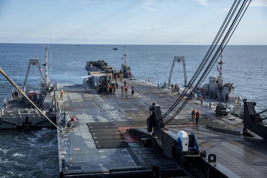 A Roll-on/Roll-off Discharge Facility and an Improved Navy Lighterage System are attached to the USNS 1st Lt. Jack Lummus with ropes and a ramp during a Marine Prepositioning Force Exercise, Aug. 19, 2015. The RRDF and INLS allowed Marines with Combat Logistics Regiment 25 and sailors with Naval Beach Group 2 to offload the Lummus using in-stream methods off the coat of Marine Corps Support Facility Blount Island, Fla. (U.S. Marine Corps photo by Sgt. Shawn Valosin/Released)