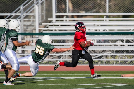 Cpl. Kyle Byrdsong, a running back for the Marine Corps Air Station Miramar Falcons, avoids a tackle while running the ball during a football game against the 1st Maintenance Battalion War Machines aboard Marine Corps Base Camp Pendleton, California, Aug. 24. The Miramar Falcons won the game with a score of 35-0. (U.S. Marine Corps photo by Cpl. Alissa P. Schuning/Released)