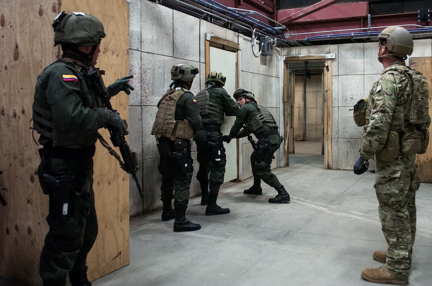 A U.S. Army Green Beret right, observes members of the Colombian Compañía Jungla Antinarcóticos simulate emplacing an explosive door-breaching charge inside a shoot house during a joint training exercise on Eglin Air Force Base, Fla., Nov. 20, 2015. The Green Beret is assigned to the 7th Special Forces Group. U.S. Army photo by Maj. Thomas Cieslak