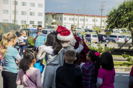 Santa Claus hugs children when he arrives for the event, Santa’s Little Helper, on Camp Hansen, Okinawa, Japan, Dec. 12, 2015. The event also had Santa fast rope out of a helicopter, fake snow, a bouncy castle, face painting and food served. The event was hosted by Combat Assault Battalion, 3rd Marine Division, III Marine Expeditionary Force and Marine Corps Community Services. (U.S. Marine Corps photo by Cpl. Tyler S. Giguere/Released)