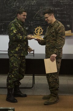 Major Claudiuv Vison presents the Marines with a plaque that symbolizes their naval heritage, thanking them for the workshop, Jan. 29. This three-day workshop, with the only battalion of Marines in Romania, covered tactics and troop-leading procedures and how the U.S. Marine Corps utilizes their noncommissioned officers in squad-sized elements. 