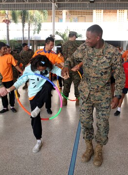 Lance Cpl. Antonio W. West Jr. plays pass the hula-hoop with a student at the Nakhon Ratchasima Panyonnookun School February 12. Marines with 1st Marine Aircraft Wing and members of the Royal Thai Air Force volunteered at the school during Exercise Cobra Gold 2015 to spend time in the community. West is a motor transportation mechanic with Marine Wing Support Squadron 171, Marine Aircraft Group 12, I Marine Aircraft Wing, III Marine Expeditionary Force, and a Seaford, Delaware, native. For more information on Exercise Cobra Gold, please visit the official Facebook page at http://www.facebook.com/ExerciseCobraGold.