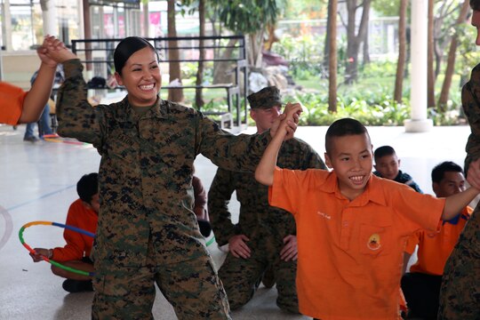 Lance Cpl. Sherry L. Eaton, a Houston, Texas, native,  celebrates with a student from the Nakhon Ratchasima Panyonnookun School after winning a game of pass the hula- hoop, February 12. Marines with 1st Marine Aircraft Wing and members of the Royal Thai Air Force volunteered at the school during Exercise Cobra Gold 2015 to spend time in the community. Eaton is an aviation technician with Marine All Weather Fighter Attack Squadron 533, attached to Marine Aircraft Group 12, 1st Marine Aircraft Wing, III Marine Expeditionary Force, under the Unit Deployment Program.  For more information on Exercise Cobra Gold, please visit the official Facebook page at http://www.facebook.com/ExerciseCobraGold.
