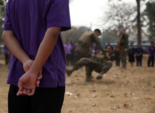 A student from Yothinnukun School watches a demonstration of Marine Corps Martial Arts Friendship Day held by Royal Thai Air Force Wing 1 and U.S. Marines at Royal Thai Air Force Base Korat during Exercise Cobra Gold 2015, Feb. 13. Students also observed demonstrations of Explosive Ordnance Disposal, Aircraft Rescue Firefighters, and Navy Corpsmen basic medical procedures. Cobra Gold 2015 is a Thailand /United States co-sponsored, multinational and joint theater security cooperation exercise, conducted annually in the Kingdom of Thailand, with 25 nations participating. This year there is an increased focus on Humanitarian Civic Action, community engagement, and medical activities to support the needs and humanitarian interests of civilian populations around the region. For more information on exercise Cobra Gold, please visit the official Facebook page at http://www.facebook.com/ExerciseCobraGold.