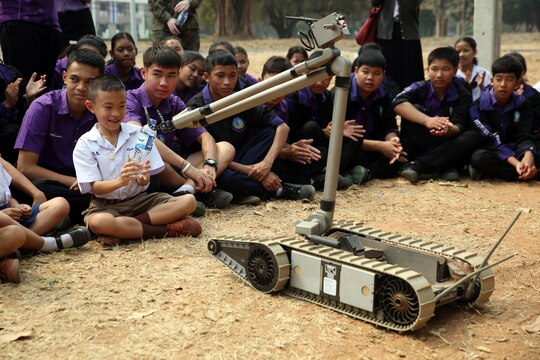 A student from Yothinnukun School receives a bottle of water from PackBot,  a robot designed to carry out dangerous missions in high-threat battlefield scenarios, at Friendship Day held by Royal Thai Air Force Wing 1 and U.S. Marines at Royal Thai Air Force Base Korat during Exercise Cobra Gold 2015, Feb. 13. Students observed demonstrations of the Marine Corps Martial Arts Program, Explosive Ordnance Disposal, Aircraft Rescue Firefighting, and Navy Corpsmen basic medical procedures. Cobra Gold 2015 is a Thailand /United States co-sponsored, multinational and joint theater security cooperation exercise, conducted annually in the Kingdom of Thailand, with 25 nations participating. This year there is an increased focus on Humanitarian Civic Action, community engagement, and medical activities to support the needs and humanitarian interests of civilian populations around the region. For more information on exercise Cobra Gold, please visit the official Facebook page at http://www.facebook.com/ExerciseCobraGold.