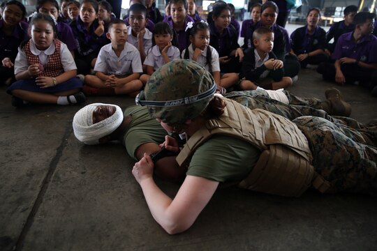 U.S. Navy Corpsmen show children from Yothinnukun School how to treat a casualty during Friendship Day held by Royal Thai Air Force Wing 1 and U.S. Marines at Royal Thai Air Force Base Korat during Exercise Cobra Gold 2015, Feb. 13. Students observed demonstrations of the Marine Corps Martial Arts Program, Explosive Ordnance Disposal, Aircraft Rescue Firefighting, and Navy Corpsmen basic medical procedures. Cobra Gold 2015 is a Thailand /United States co-sponsored, multinational and joint theater security cooperation exercise, conducted annually in the Kingdom of Thailand, with 25 nations participating. This year there is an increased focus on Humanitarian Civic Action, community engagement, and medical activities to support the needs and humanitarian interests of civilian populations around the region. For more information on exercise Cobra Gold, please visit the official Facebook page at http://www.facebook.com/ExerciseCobraGold.