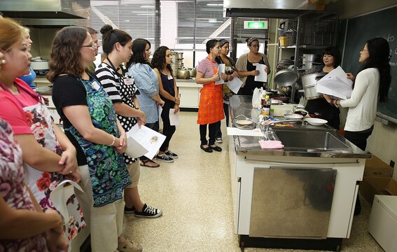 Mikie Watanabe, cultural adaption specialist, right, and Sachiko Tamura, left, a member of Eating Habits Improvement Promotion, begin to instruct a Japanese cooking class at Fukushi Kaikan in Iwakuni City, Japan, July 24, 2015. The station’s cultural adaptation program coordinates the class three times a year, and it is one of many ways to indulge in local cuisine. In this specific class, guests learned to make handmade Shumai, Wakame soup and traditional fried rice.
